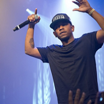Black male rapper on stage with arms in air holding a mic