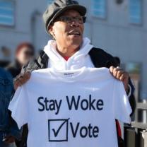 Woman holding T-shirt saying Stay Woke Vote