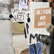 People outside holding signs that say Inclusion Not Hate and Greg Anglin takes Nazi Money