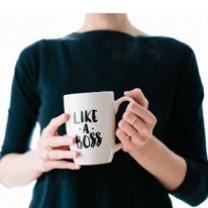 Woman's torso with hands holding mug that says Like a Boss