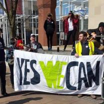 People holding a Yes We Can sign outside a brick building