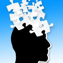 Black silhouette of a head facing right with white puzzle pieces flying out of his head against a blue background