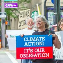 Woman holding a sign saying Climate Action It's our Obligation