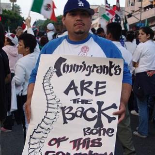 Man holding sign saying Immigrants are the Backbone of this country