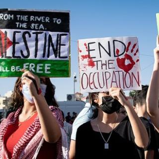 From left to right, protest signs read: "From the river to the sea Palestine will be free", "End the occupation", "End apartheid."