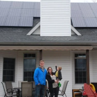 Solar panels on home with man, woman and child out front