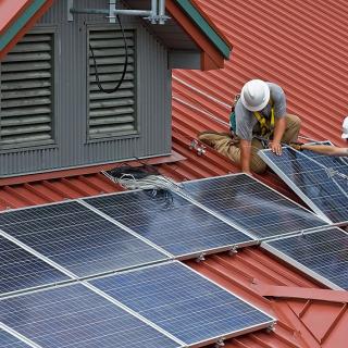 Men installiing solar panels on a roof