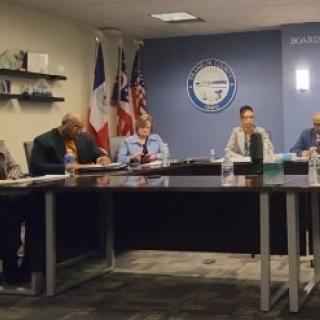 The hearing panel seated at a long table