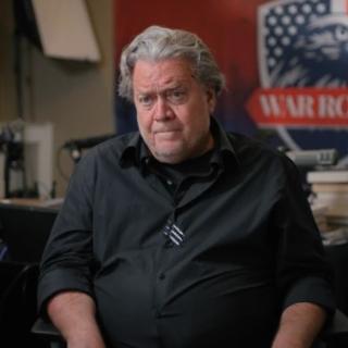 Gray haired white man by a sign reading War Room