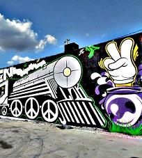 Mural with a train and peace signs for the wheels and a hand with two fingers up in a peace sign