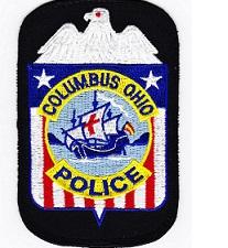 A patch with a white eagle on top, red, white and blue with stars and stripes and the words Columbus Police and what looks like the Santa Maria in the middle