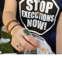 Woman from neck down wearing black T-shirt with words Stop Executions Now