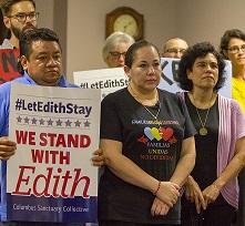 Latino people posing for camera looking grim, one man holding a sign that says #LetEdithStay We Stand with Edith
