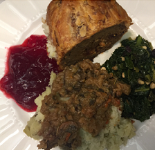 Top down view of a white plate with red cranberry sauce, a brown skinned potato something green and leafy on the side and what looks like rice with something brown on top