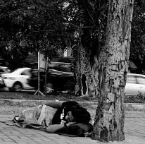 Black and white photo of person lying on the ground under a tree