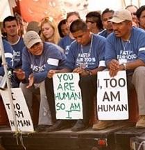 Latino men wearing blue shirts sitting and holding signs that say I Too, Am Human