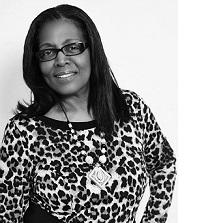 Black and white photo of a black woman with shoulder length hair, black rimmed glasses, a leopard print top and a necklace