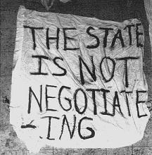 A crudely hand lettered sign on what looks like a sheet saying The state is not negotiating