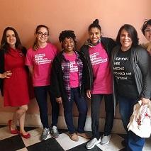 Young white and black women posing in a row with arms around each other smiling and wearing pink NARAL T-shirts