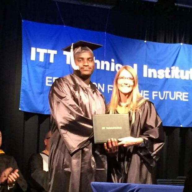 Black man in graduation robe and hat receiving diploma