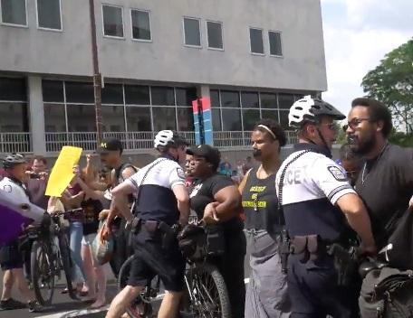 Police al suited up with helmets and bikes attacking stationary black people with black tape over their mouths
