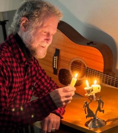 Bill Cohen with candle and guitar