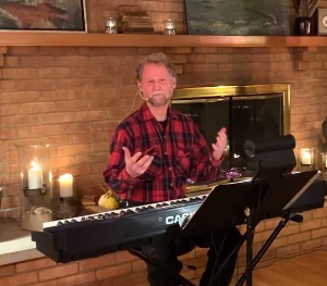 White man at a keyboard in front of a fireplace