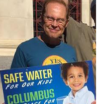 White man smiling and holding a sign saying Safe Water for our Kids