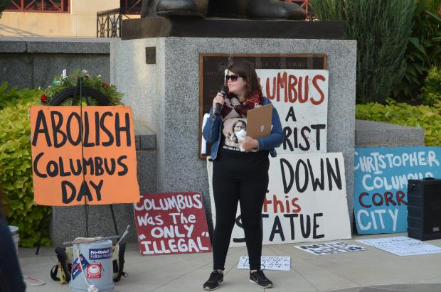 Woman in front of signs talking into a microphone