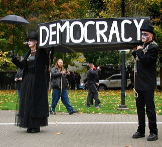 People in a funeral procession holding a democracy sign