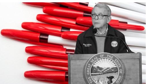Governor Dewine at a podium in front of red pens