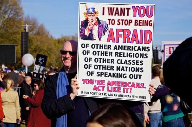 Man outside holding a sign about what Americans fear