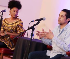 Two people on stage talking into mics