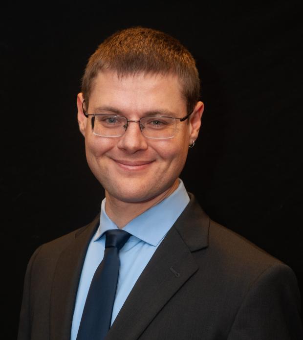 White man in a suit and glasses smiling