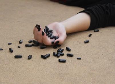 LIfeless hand with pills scarttered around