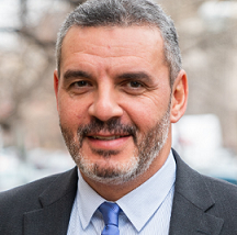 Man with salt and pepper hair and beard in a suit