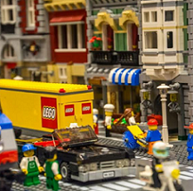 Storefronts made from legos and Lego word on side of truck and little lego people 