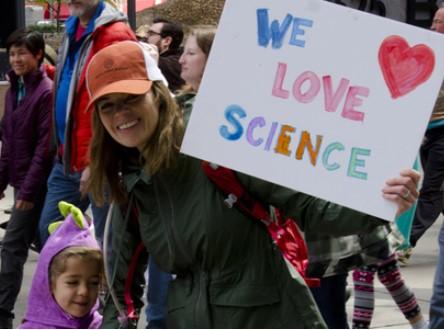 Woman with child and sign saying We Love Science