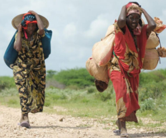 Immigrant women walking on dirt path in Africa