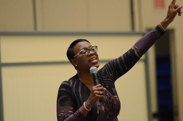 Black woman giving a speech raising her arm in the air