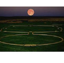 Green ground and dusky sky with huge red moon and a design on the ground