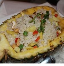 Pineapple cut in half with lots of rice and vegetables inside