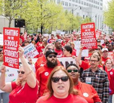 Huge outdoor march with everyone wearing red T-shirts and holding signs that say Fighting for Schools