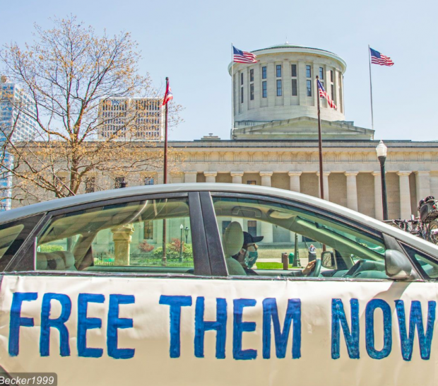 Car with sign saying Free Them Now in front of Ohio Statehouse