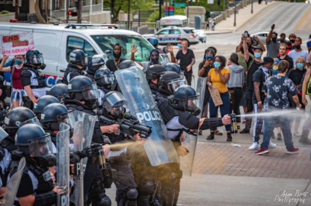 Police spraying a crowd of protestors