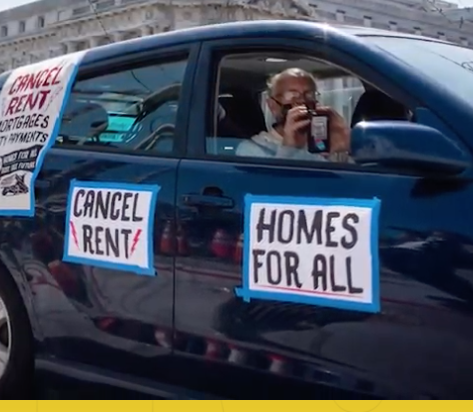 Person in car in caravan with sign Homes for All