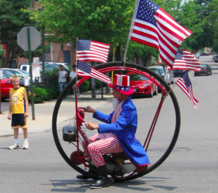 Uncle Sam in a round bike with flags in the parade