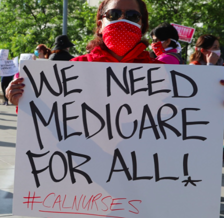 Person holding sign saying We Need Medicare for All