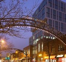 Lighted metal arch over street next to tall building
