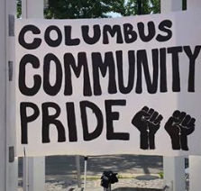 Big white outdoor sign saying Columbus Community Pride with two fist drawings